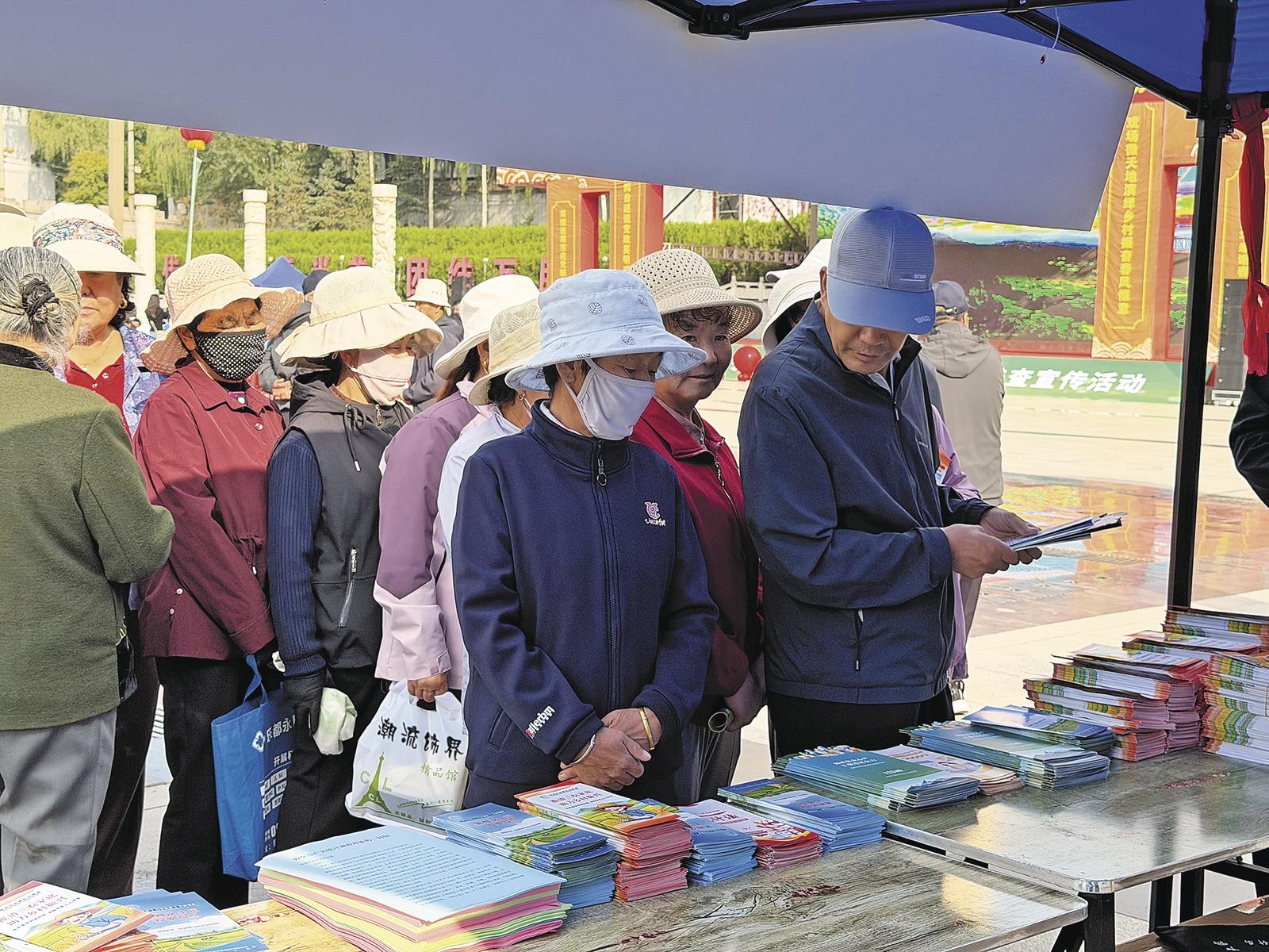 活动现场,市民排队领取宣传手册。本报记者 王菲菲 摄